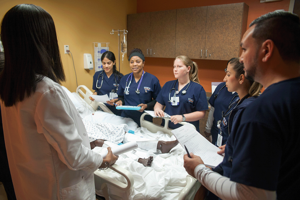 Multiple Utica students observing vitals in a clinical setting