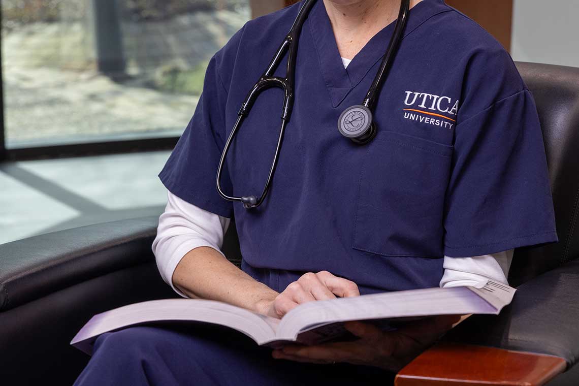Utica University student holding textbook
