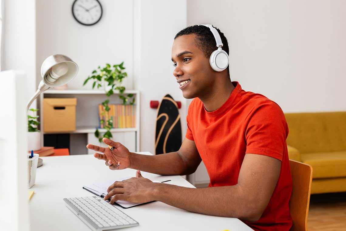 student sitting at computer with headphones