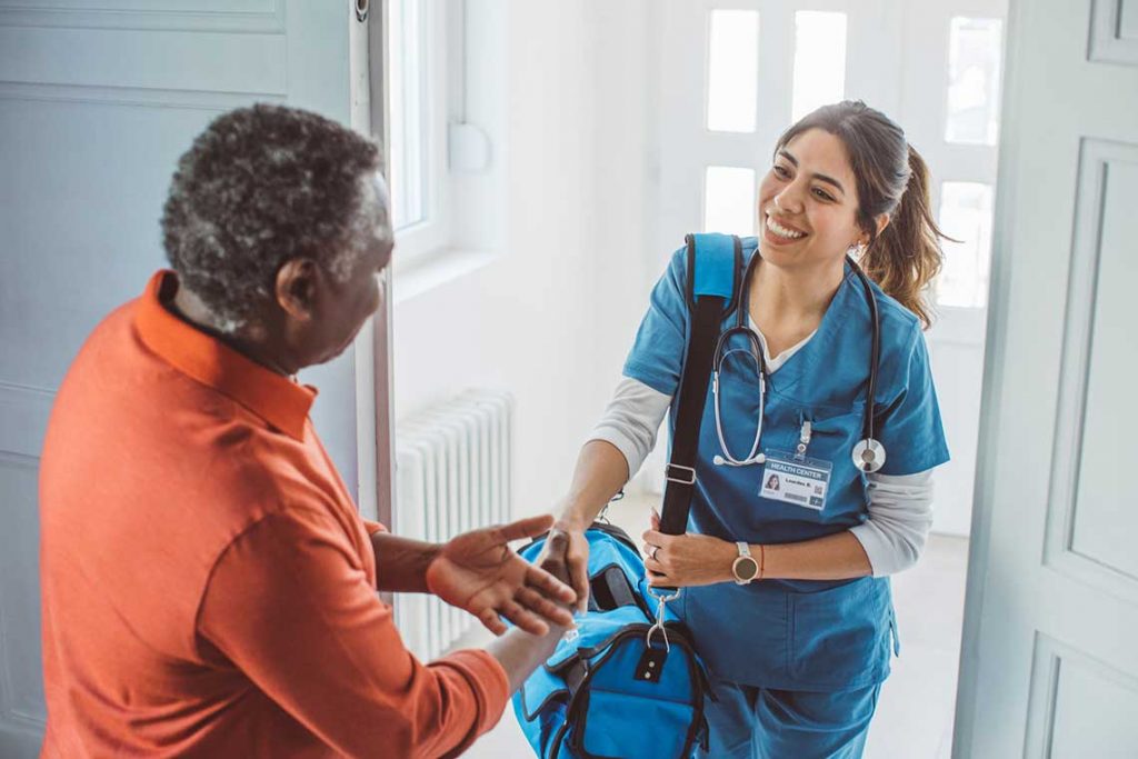 nurse shaking patient's hand at home entryway
