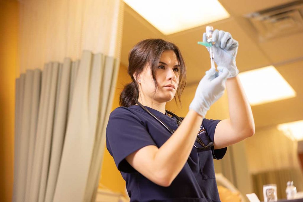 Utica ABSN student holding syringe in sim lab